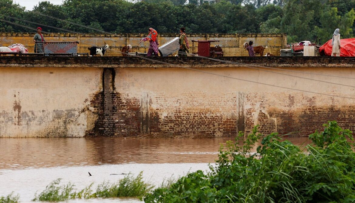 A family with their belongings takes refuge over a roof of their house near Chenab River, following the monsoon rains and rising water level in Wazirabad, in Punjab on August 27, 2025. — Reuters