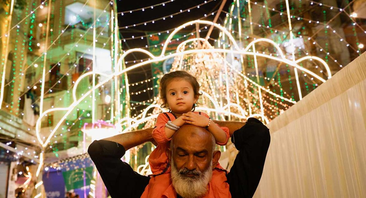 A girl sits on the shoulders of her grandfather as they visit an illuminated street ahead of Eid e Milad-ul-Nabi, the birth anniversary of Prophet Mohammad (PBUH), in Karachi, September 5, 2025. — Reuters