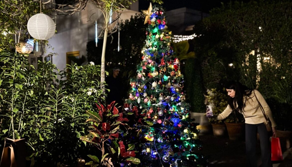 A woman photographs a Christmas tree at the Alliance Française de Karachi. — Reporter