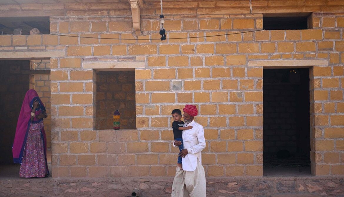 Image shows herdsman Sawai Singh Bhatis father, Khet Singh carrying his grandson at their house in Sanwata village on the outskirts of Rajasthans Jaisalmer city.— AFP