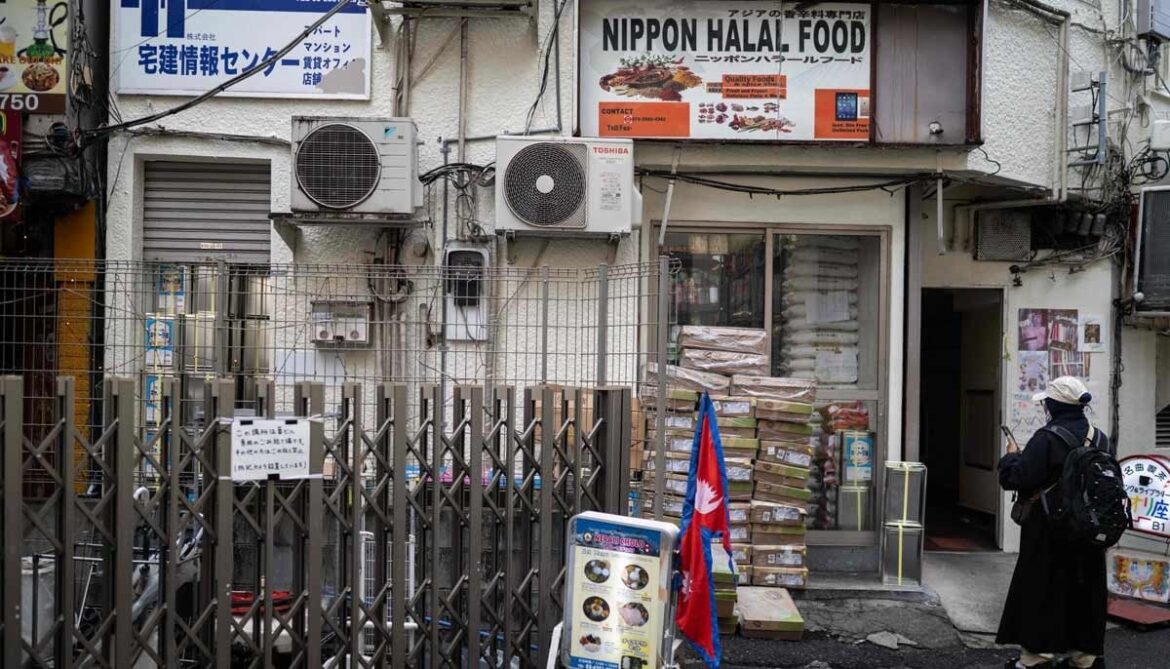 A woman stands near a South Asian store in the Okubo area, one stop north of Shinjuku metro, in Tokyo on June 12, 2026. — AFP