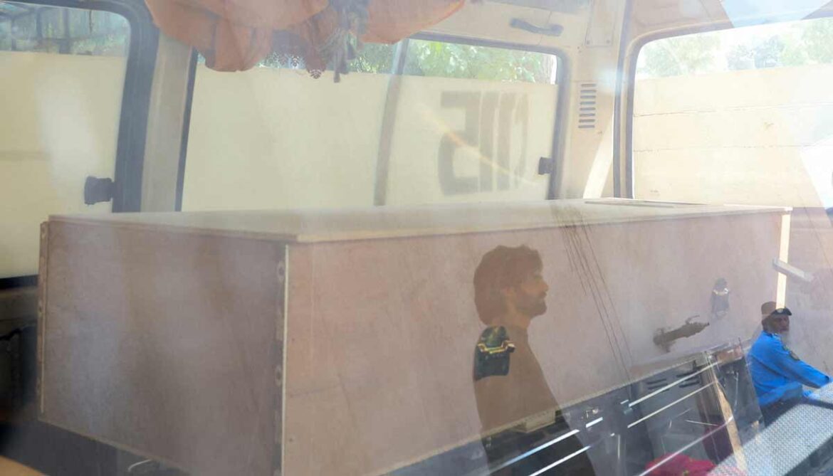 Men are reflected in the glass window of an ambulance as a coffin carrying a victim is placed inside, following a deadly fire at the Pakistan Institute of Medical Sciences (PIMS) hospital in Islamabad, Pakistan, on August 26, 2026.— Reuters