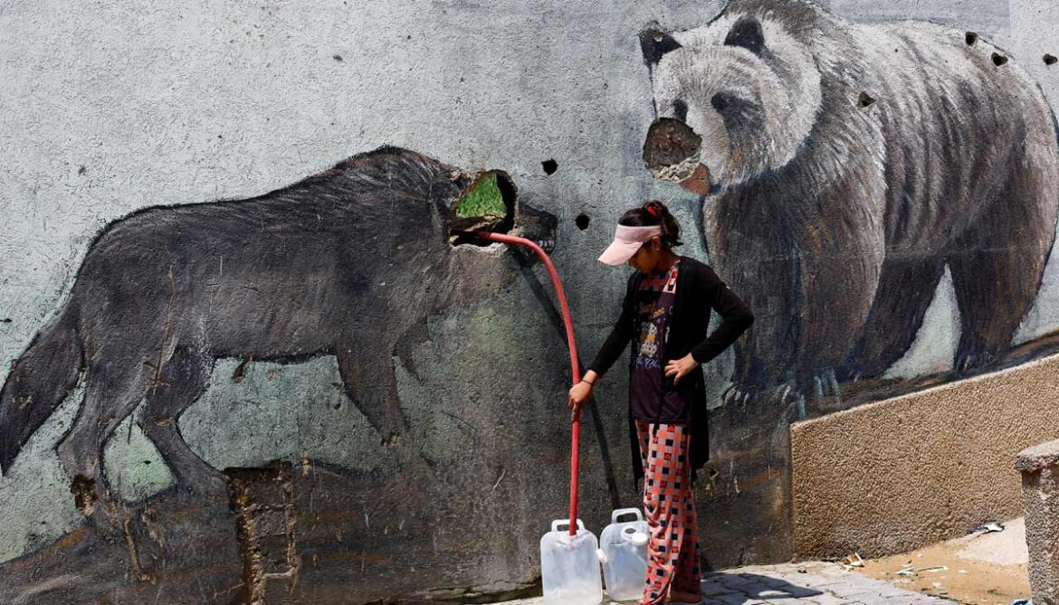 A Palestinian girl fills water containers outside the wall of a zoo damaged during the war, in Gaza City, August 15, 2026.— Reuters
