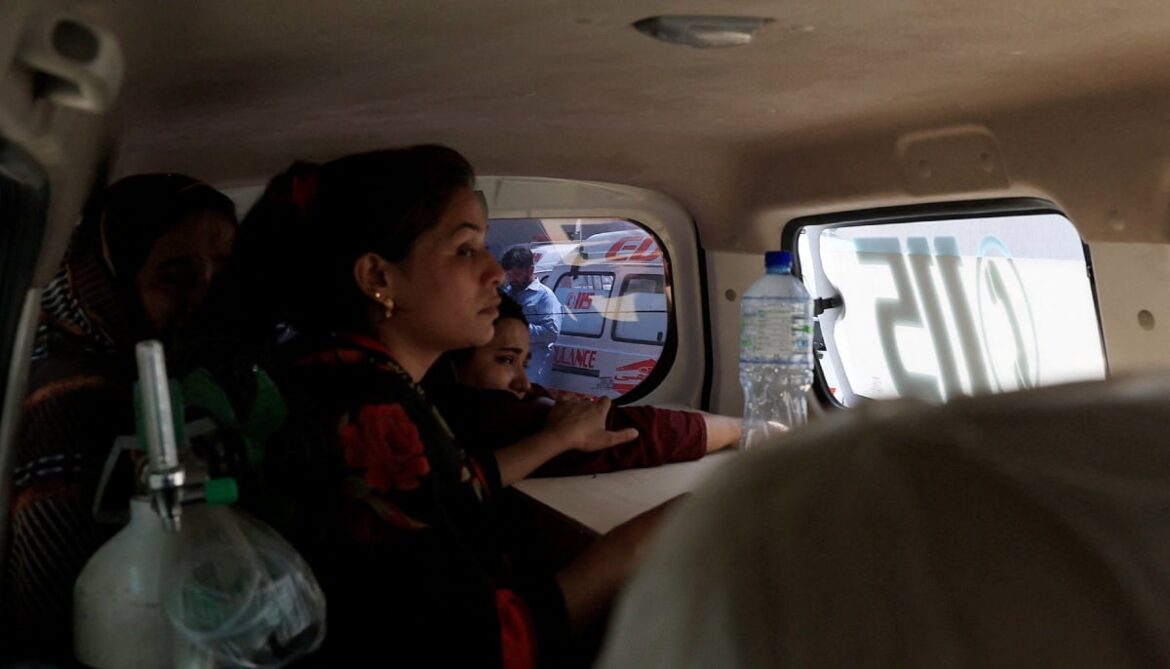 Javeria, mother of a newborn victim, holds onto a coffin containing the body of her newborn inside an ambulance following a deadly fire at the Pims hospital in Islamabad, on August 26, 2026. — Reuters